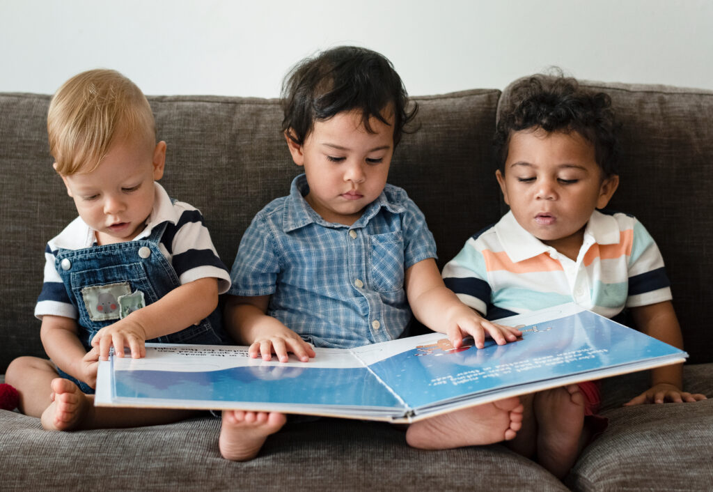 three toddlers looking at a picture book