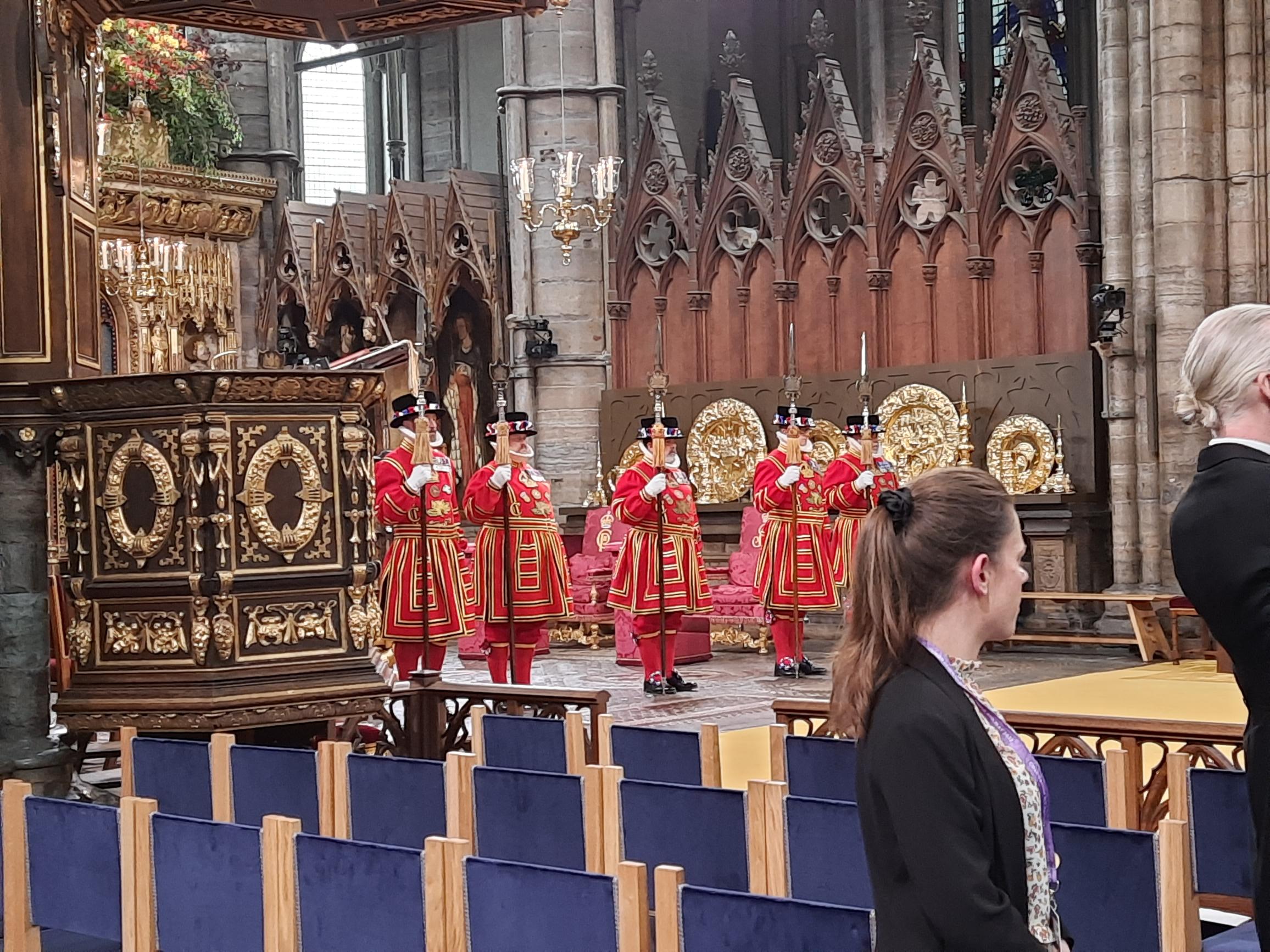 A view of five yeomen in red uniforms with large spears. They are guarding the main section of Westminster Abbey that was used for the Coronation.
