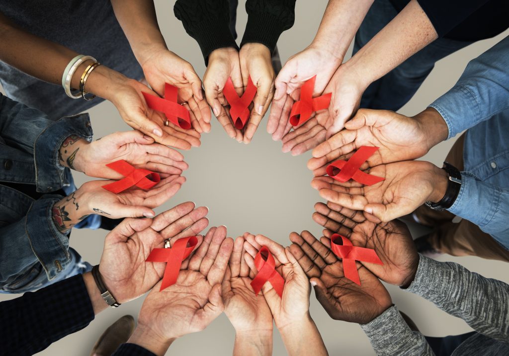 A group of adults showing hands with red ribbons placed in the centre
